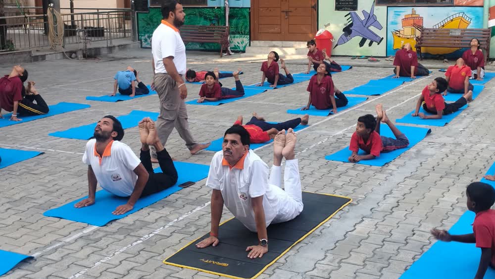 Schoolchildren practising yoga poses outdoors on International Yoga Day